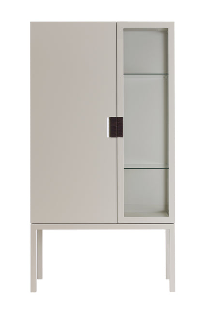 Designed by Anya Sebton and Eva Lilja Löwenhielm 2014.  Glass cabinet in lacquered MDF, stand in lacquered metal. The left side has a covered door and a covered side with two lacquered shelves and the right side has a glass door and a glass side with two glass shelves. Doors have twined leather handles. 