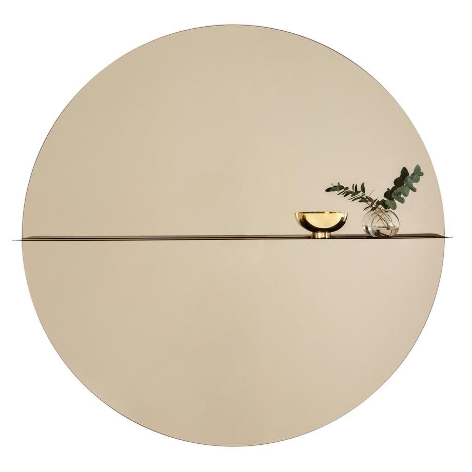 Designed by Anya Sebton and Eva Lilja Löwenhielm 2016.  Round mirror with a horizontal metal shelf. Metal wall fixture included. Screws for attachment against the wall are not included.