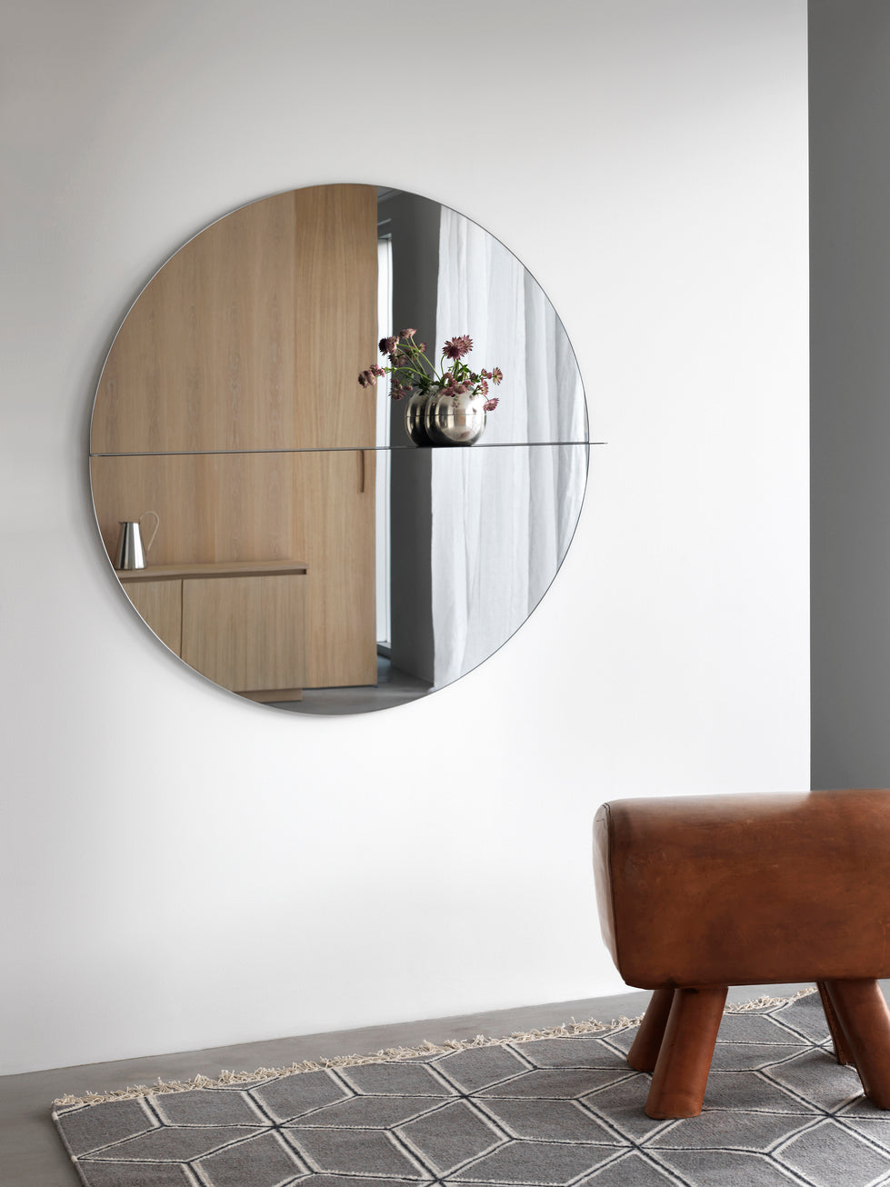 Designed by Anya Sebton and Eva Lilja Löwenhielm 2016.  Round mirror with a horizontal metal shelf. Metal wall fixture included. Screws for attachment against the wall are not included.